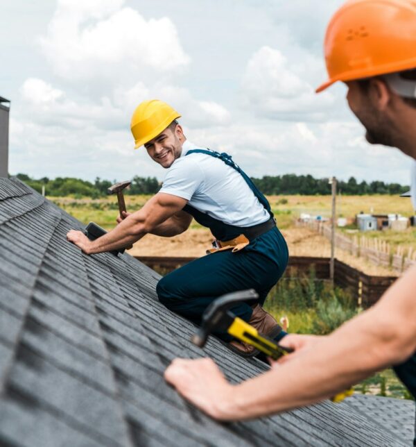 selective focus of happy repairman looking at coworker on roof